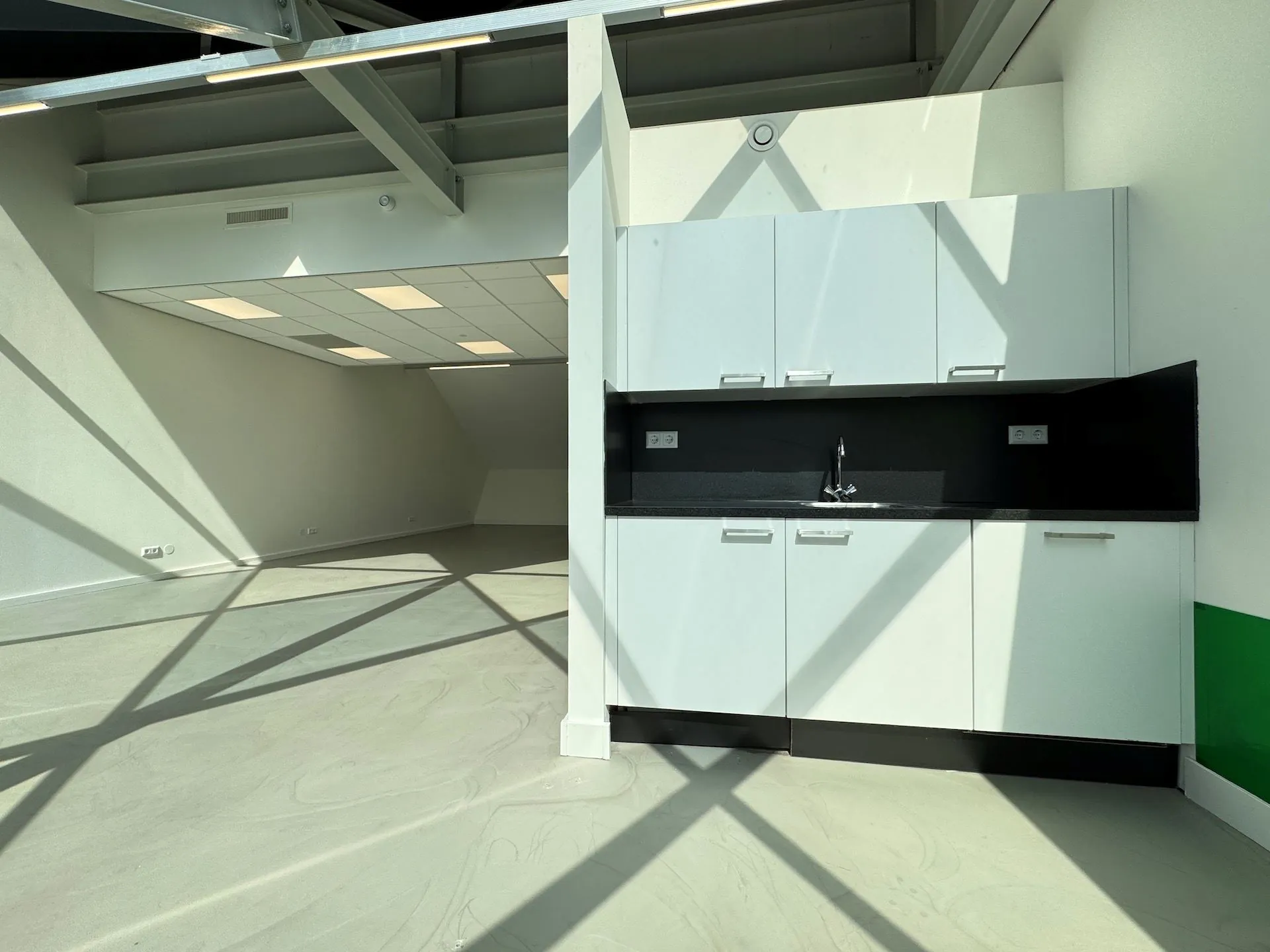 Moderne, lege kantoorruimte met een witte pantry en veel natuurlijk licht in het Mart Stamhof-gebouw.